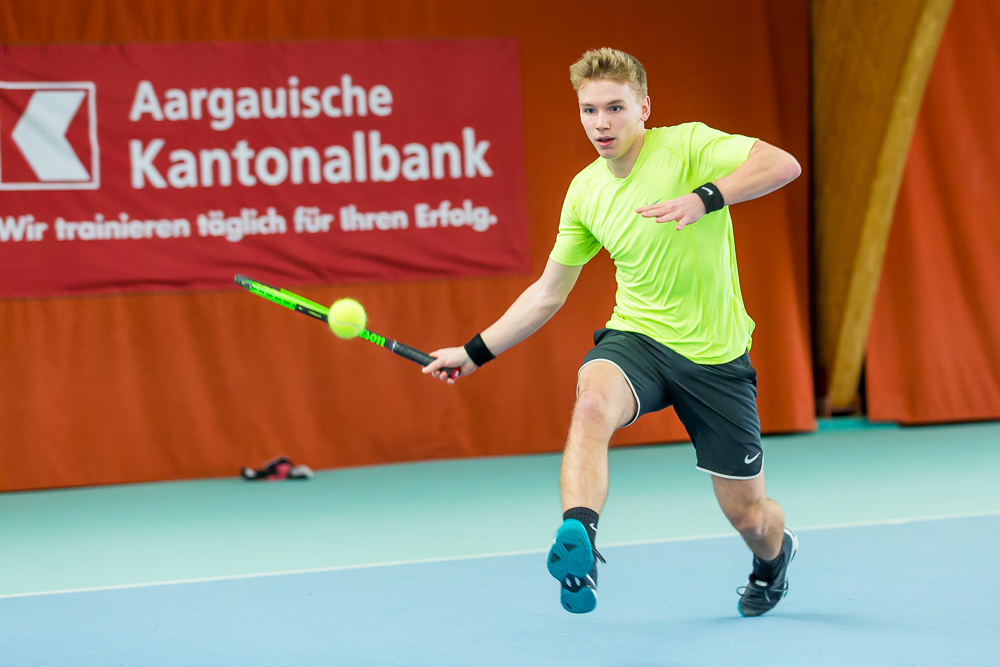 Ein junger Tennisspieler schlägt eine Vorhand aus vollem Lauf