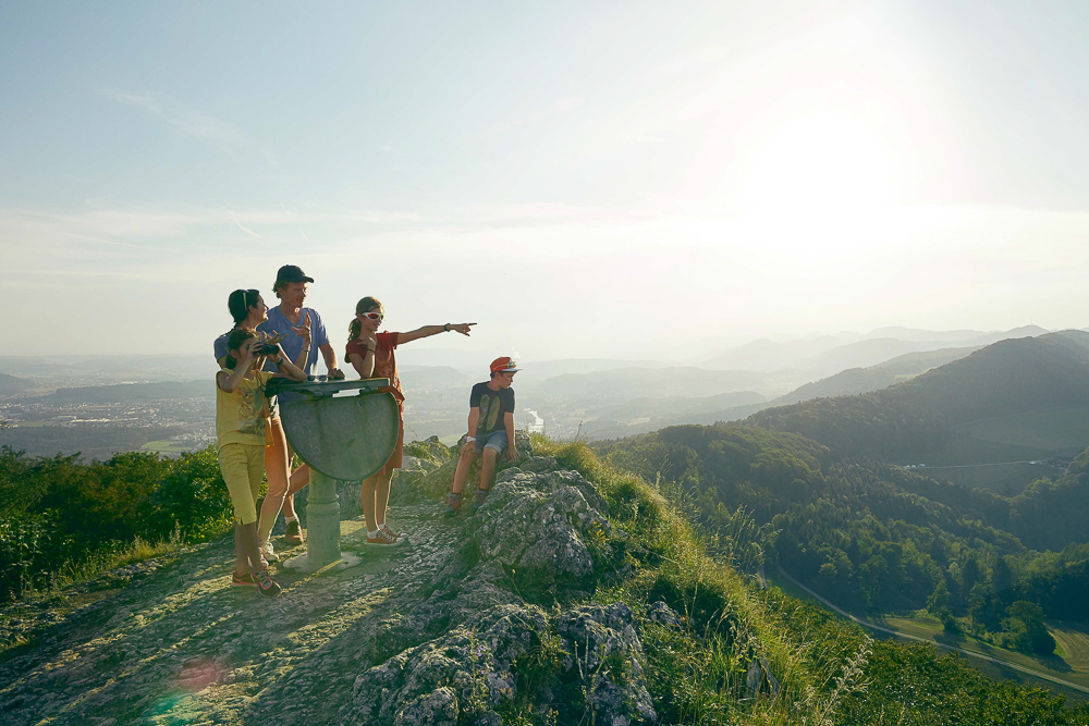 Eine Familie geniesst den Ausblick auf einem Hügel