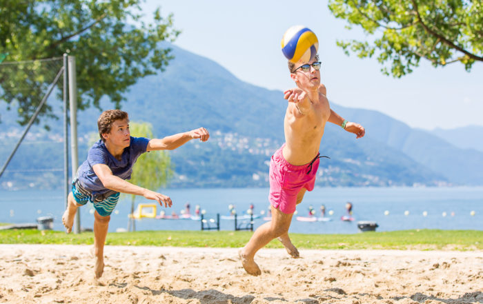 Zwei Jungs spielen Beachvolleyball und hechten nach einem Ball