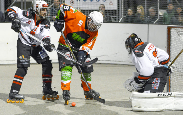 Zwei Inline Hockeyspieler im Direktduell vor dem Tor