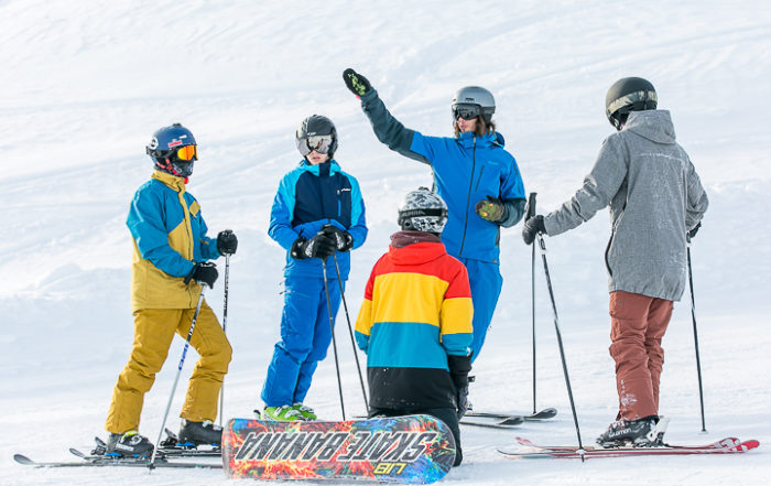 Ein Leiter erklärt vier Jugendlichen Ski- und Snowboardfahrern eine Übung im Jugendsportcamp des Kantons Aargau